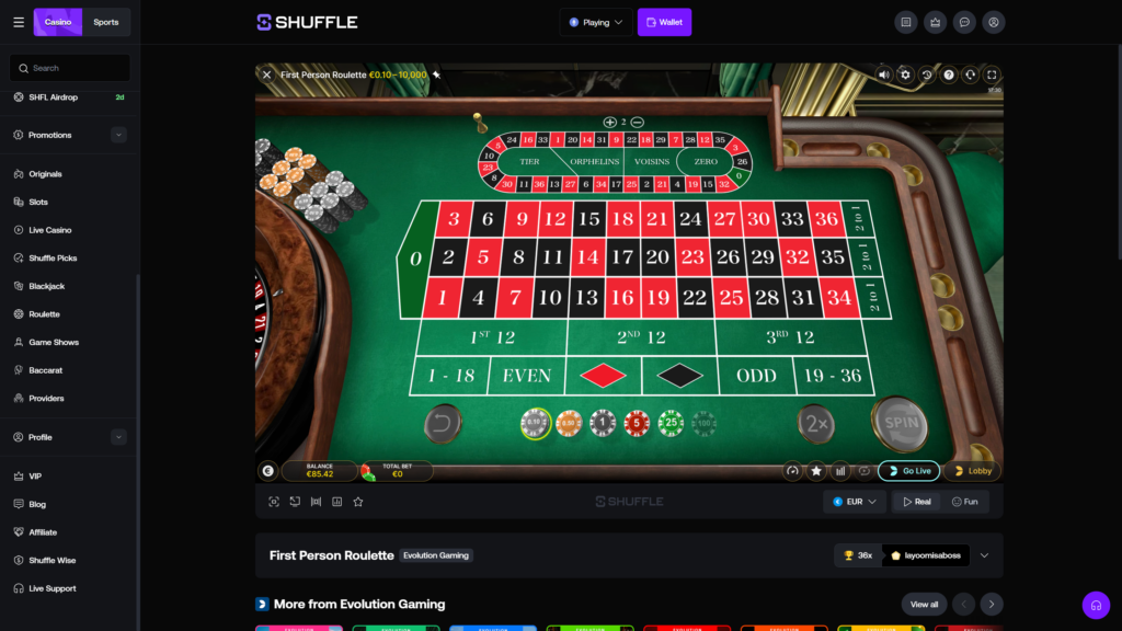 Shuffle.com online crypto casino First Person Roulette game by Evolution Gaming displayed in immersive 3D view, featuring a polished wooden roulette wheel on the left with a glimpse of the spinning numbered pockets and burlwood housing, full European single-zero green felt betting layout showing all numbers from 0 to 36 arranged in three rows with red and black colour coding plus the green zero pocket, dedicated racetrack betting section at the top displaying TIER, ORPHELINS, VOISINS and ZERO neighbour bets with surrounding number sequences, outside betting options for 1-18, EVEN, Red diamond, Black diamond, ODD and 19-36, plus 1st 12, 2nd 12 and 3rd 12 dozen sections and three 2 to 1 column bets on the right, chip selection bar showing denominations of 0.10, 0.50, 1, 5, 25 and 100 with the 0.10 chip currently selected, large gold SPIN button and 2x rebet button on the right, undo button on the left, table betting limits displayed as €0.10–10,000, current balance €85.42 and total bet €0 in the bottom info bar, 17:30 round timer in the top-right, EUR currency selector with Real and Fun mode toggles, Go Live and Lobby action buttons, Shuffle sidebar showing Casino navigation including Originals, Slots, Live Casino, Shuffle Picks, Blackjack, Roulette, Game Shows, Baccarat, Providers, VIP, Blog, Affiliate, Shuffle Wise and Live Support menu items, and the First Person Roulette Evolution Gaming footer banner showing a 36x maximum payout achieved by player layoomisaboss